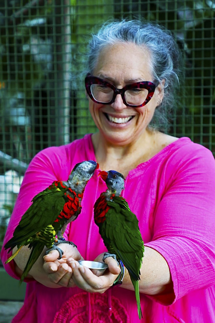 Carolyn Podruchny smiling while holding two parrots